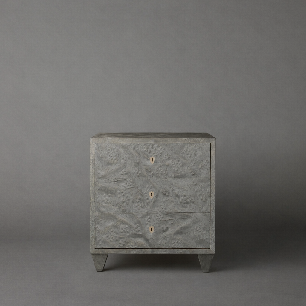 Gray textured three-drawer dresser against a gray background