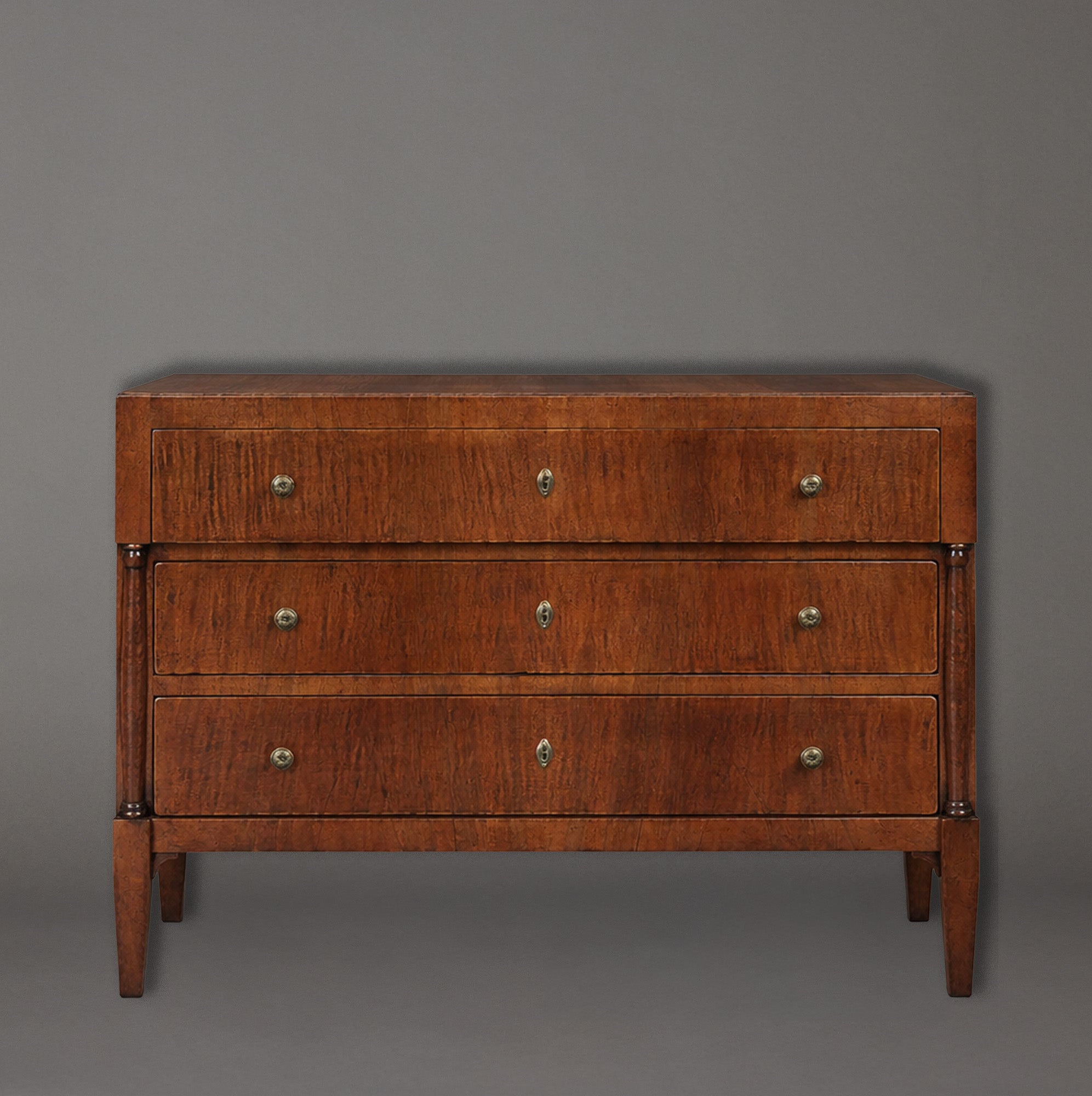 Wooden dresser with three drawers on a gray background